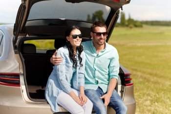 travel, summer vacation, road trip, leisure and people concept - happy couple hugging at open trunk of hatchback car outdoors