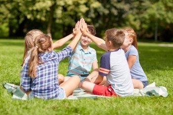 summer holidays, friendship, childhood, leisure and people concept - group of happy pre-teen kids making high five gesture in park