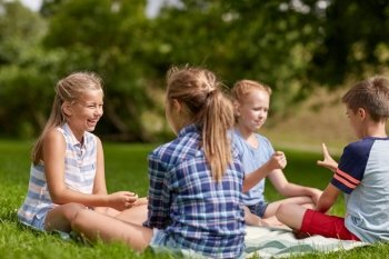 summer holidays, entertainment, childhood, leisure and people concept - group of happy pre-teen kids playing rock-paper-scissors game in park
