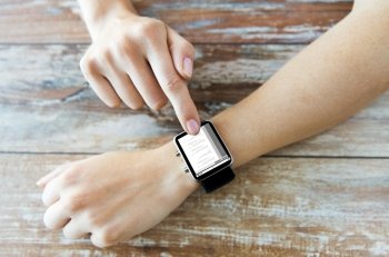 business, modern technology, programming and people concept - close up of female hands setting smart watch with coding on screen on wooden table