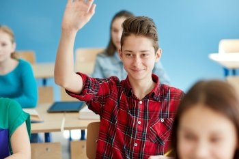 education, learning and people concept - happy student boy raising hand at school lesson