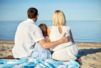 vacation, summer holidays, travel, adoption and people concept - happy family hugging on summer beach