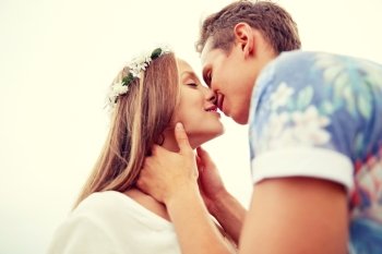 summer holidays, love, romance and people concept - happy smiling young hippie couple kissing outdoors