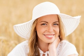 nature, summer holidays, vacation and people concept - close up of happy young woman in white dress and sun hat enjoying sun on cereal field