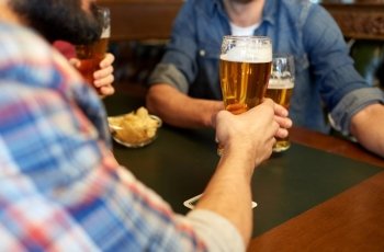 people, leisure, drinks and celebration concept - happy male friends drinking beer at bar or pub