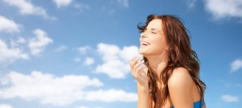 travel, tourism, summer vacation and people concept - happy beautiful woman over blue sky and clouds background