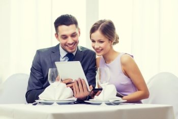 restaurant, couple, technology and holiday concept - smiling young woman looking into boyfriends or husbands menu on tablet pc computer
