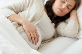 pregnancy, rest, people and expectation concept - pregnant woman sleeping in bed at home