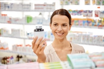 medicine, pharmaceutics, health care and people concept - happy female customer with drug jar at pharmacy. happy female customer with drug jar at pharmacy