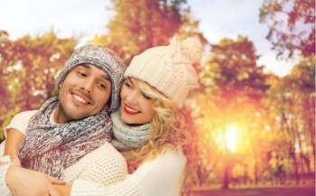 season, people, love and fashion concept - happy family couple in warm clothes over autumn background and sunlight