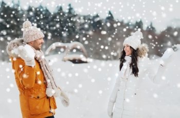 people, season, love and leisure concept - happy couple playing snowballs in winter
