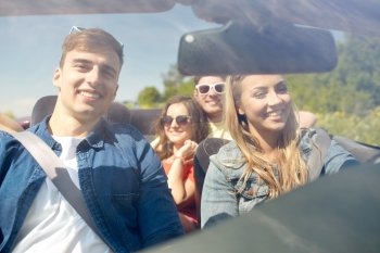 leisure, road trip, travel and people concept - happy friends driving in cabriolet car along country road