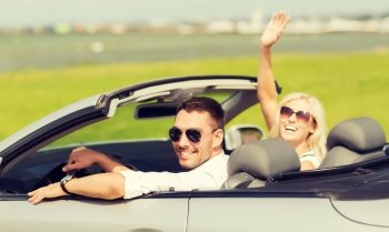 transport, road trip, leisure, gesture and people concept - happy man and woman driving in cabriolet car and waving hand
