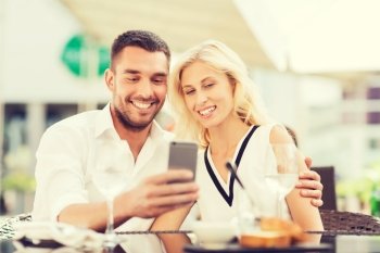 love, date, technology, people and relations concept - smiling happy couple taking selfie with smatphone at city street cafe