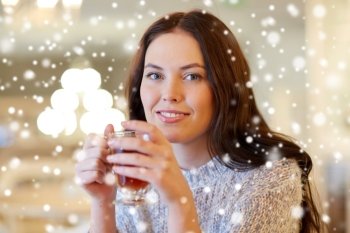 leisure, drinks, people and lifestyle concept - smiling young woman drinking tea at cafe