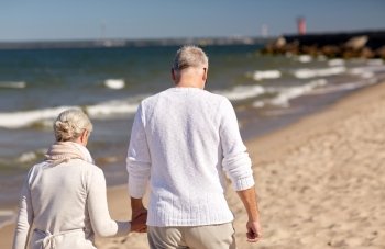 family, age, travel, tourism and people concept - happy senior couple holding hands and walking along summer beach