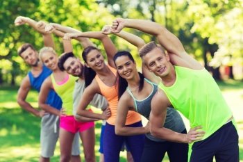 fitness, sport, friendship and healthy lifestyle concept - group of happy teenage friends or sportsmen exercising and stretching at boot camp