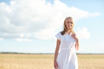 happiness, nature, summer, vacation and people concept - happy smiling young woman or teenage girl on cereal field