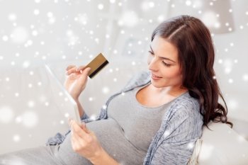 pregnancy, online shopping, technology, winter and people concept - happy pregnant woman with tablet pc computer and credit card at home over snow