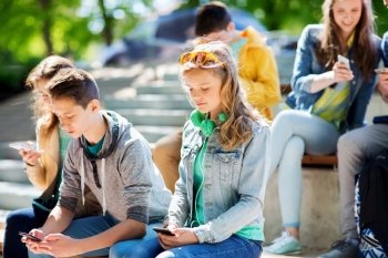 technology, internet addiction and people concept - teenage friends with smartphones outdoors