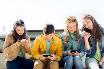technology, internet addiction and people concept - happy teenage friends with smartphones outdoors