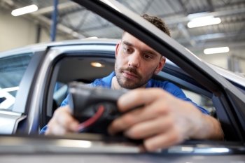 service, repair, maintenance and people concept - mechanic man with automotive diagnostic scanner checking car system at workshop