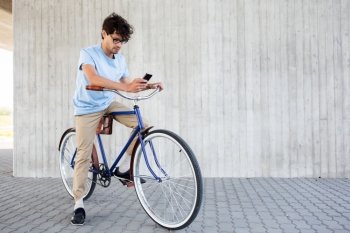 people, communication, technology, leisure and lifestyle - hipster man texting on smartphone with fixed gear bicycle on city street
