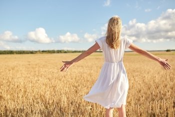 country, nature, summer holidays, vacation and people concept - happy young woman in white dress on cereal field