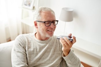 technology, people, lifestyle and communication concept - of happy senior man using voice command recorder or calling on smartphone at home