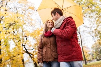 love, relationship, season, family and people concept - happy couple with umbrella walking in autumn park
