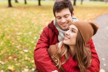 love, relationships, season and people concept - happy young couple hugging in autumn park