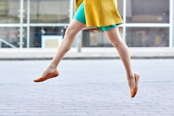 fashion and people concept - happy young woman or teenage girl legs flying above pavement on city street. young woman or teenage girl legs on city street