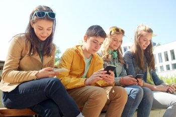 technology, internet and people concept - group of happy teenage friends with smartphone and headphones outdoors