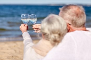 family, age, holidays, leisure and people concept - close up of happy senior couple clinking wine glasses on summer beach