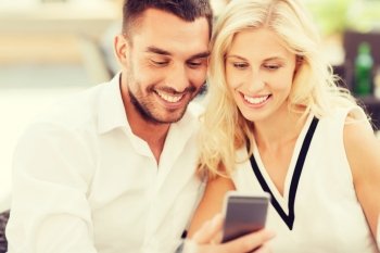 love, date, technology, people and relations concept - smiling happy couple with smartphone at city street cafe