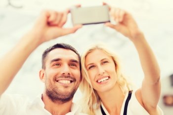 love, date, technology, people and relations concept - smiling happy couple taking selfie with smartphone outdoors