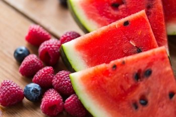 healthy eating, food, dieting and vegetarian concept - close up of raspberry, blueberry and watermelon slices on wooden table