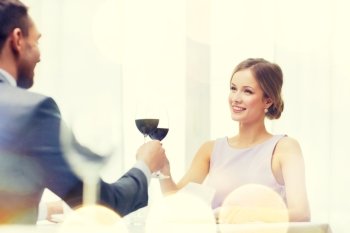 restaurant, couple and holiday concept - smiling young woman with glass of red wine looking at boyfriend or husband at restaurant