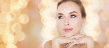 beauty, people and bodycare concept - beautiful young woman face and hands over holidays lights background