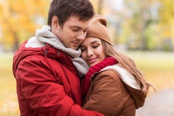 love, relationships, season and people concept - close up of happy young couple hugging in autumn park