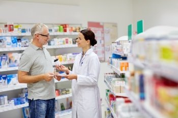 medicine, pharmaceutics, health care and people concept - happy pharmacist giving drug to senior man customer and taking prescription at drugstore