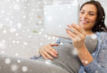 pregnancy, motherhood, technology, people and expectation concept - close up of happy pregnant woman with tablet pc computer at home over snow