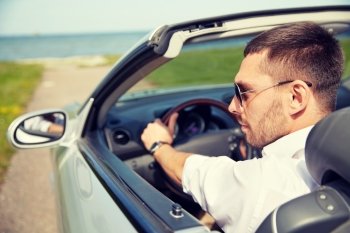 road trip, travel, transport, leisure and people concept - happy man driving cabriolet car outdoors