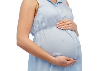 pregnancy, motherhood, people and expectation concept - close up of pregnant woman touching her big belly over white background