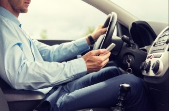 transport, business trip, technology and people concept - close up of young man with smartphone driving car
