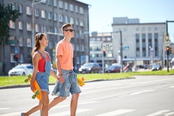 summer holidays, extreme sport and people concept - happy teenage couple with short modern cruiser skateboards crossing city crosswalk
