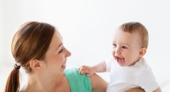 family, child and parenthood concept - happy smiling young mother with little baby at home