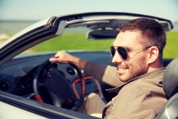 road trip, travel, transport, leisure and people concept - happy man driving cabriolet car outdoors