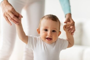 family, child, childhood and parenthood concept - happy little baby learning to walk with mother help at home