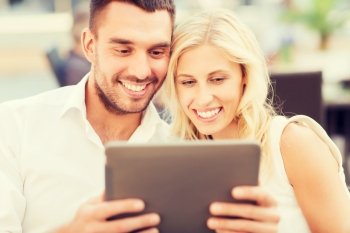 love, dating, people, technology and holidays concept - happy couple with tablet pc computer at restaurant lounge or terrace